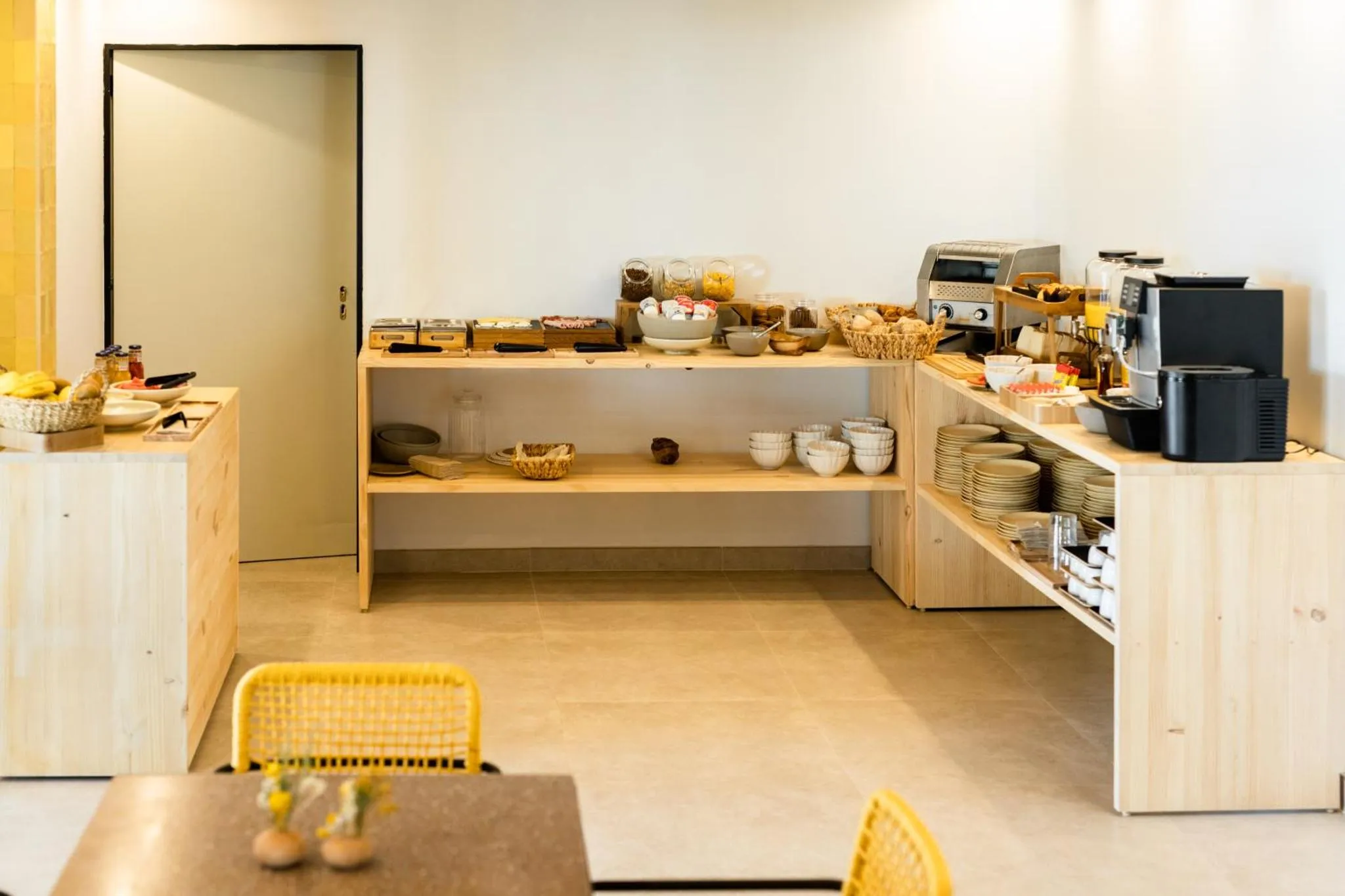Un buffet propose des viennoiseries et des boissons dans une salle lumineuse.