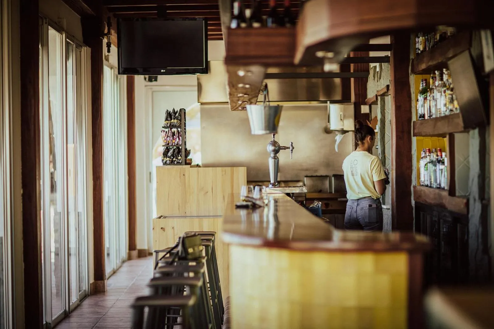 Un bar avec un comptoir en bois et une personne qui travaille.