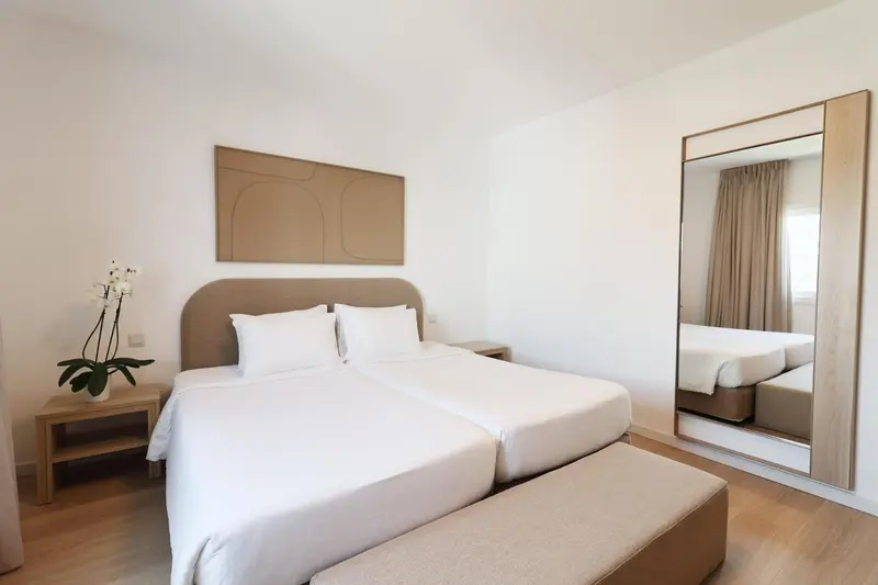 Une chambre lumineuse avec un grand lit et un miroir.