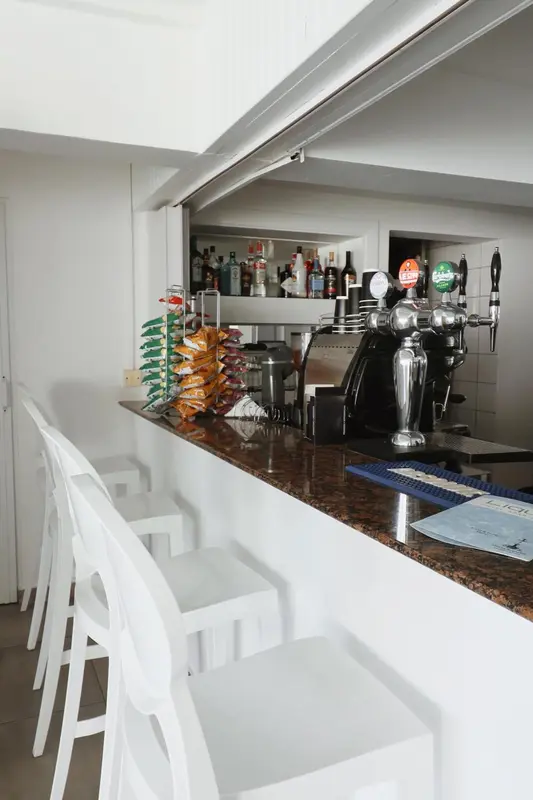 Un comptoir de bar blanc avec des bouteilles et des verres.