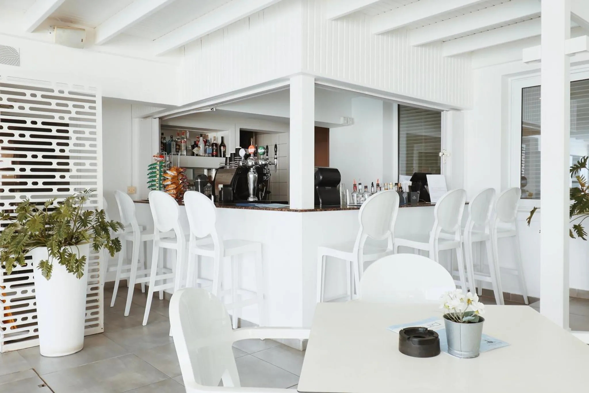 Un bar blanc avec des tabourets et une table à manger en plastique.