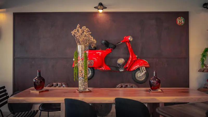 Une table en bois est mise en valeur par une moto rouge vintage accrochée au mur.