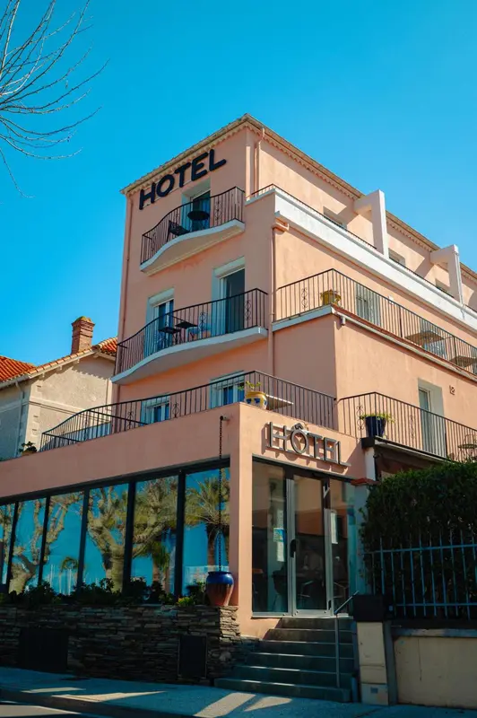 Façade d'un bâtiment rose avec des balcons et une devanture vitrée.