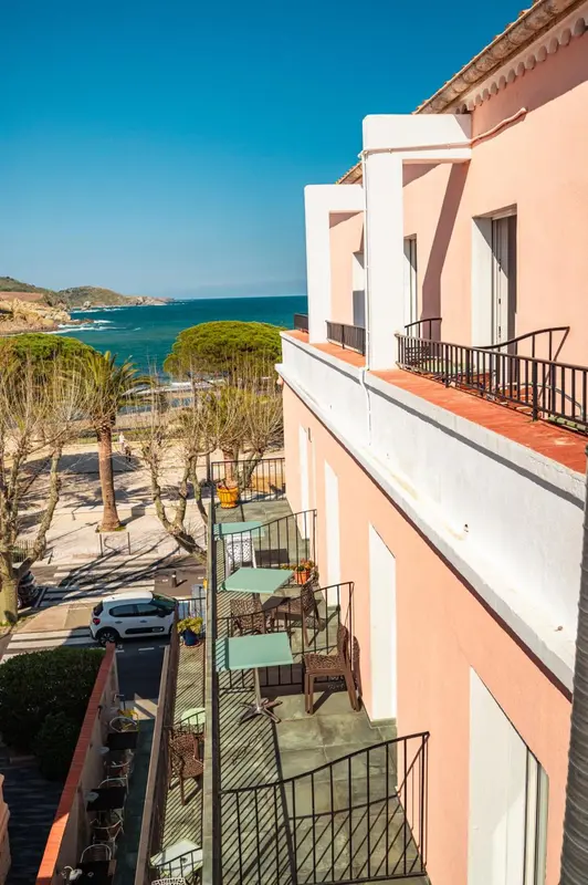 Façade d'un bâtiment rose avec des balcons donnant sur la mer.