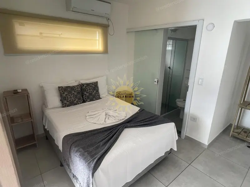 Une chambre lumineuse avec un lit recouvert d'une couverture blanche et de coussins.