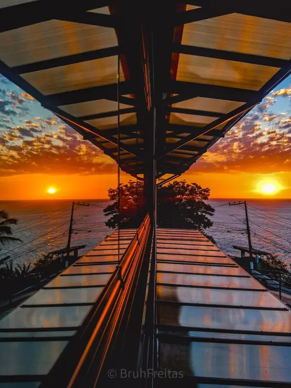 Un ponton en bois s'avance vers un coucher de soleil flamboyant sur l'océan.