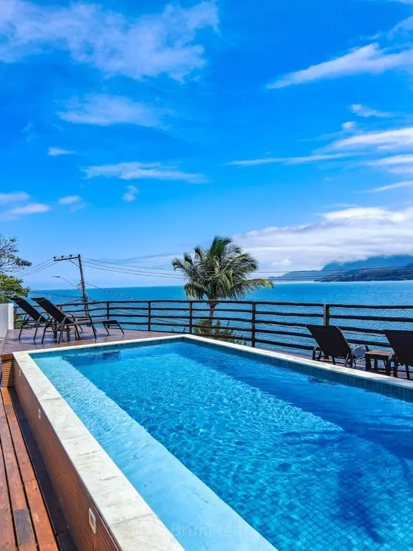 Une piscine à débordement offre une vue sur la mer et le ciel bleu.