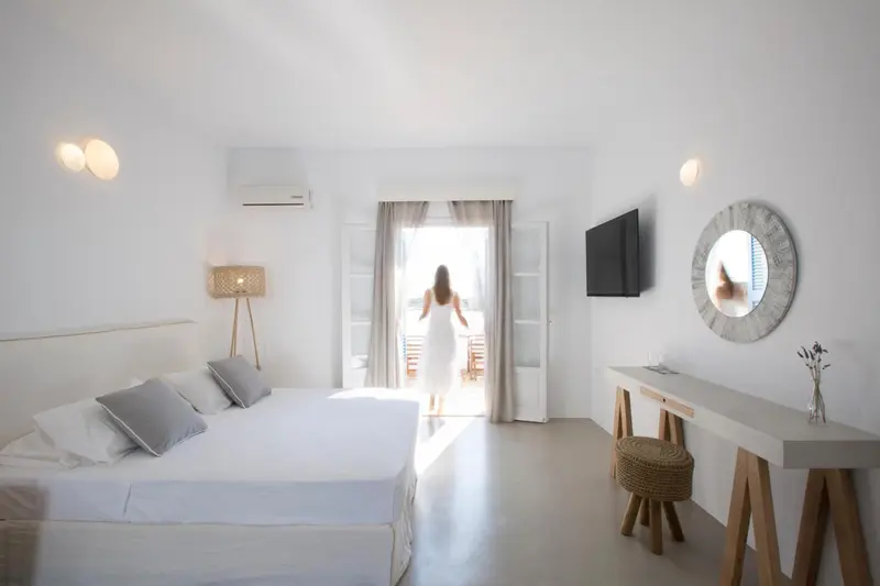 Une chambre lumineuse s'ouvre sur une terrasse par une porte cintrée.