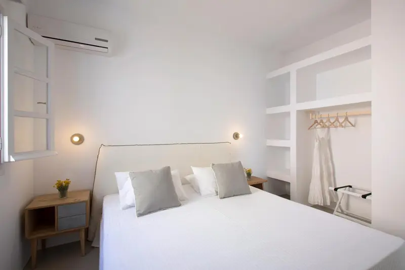 Une chambre lumineuse avec un lit fait et des coussins gris.