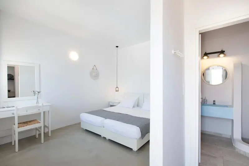 Une chambre lumineuse avec un lit double et un coin coiffeuse.