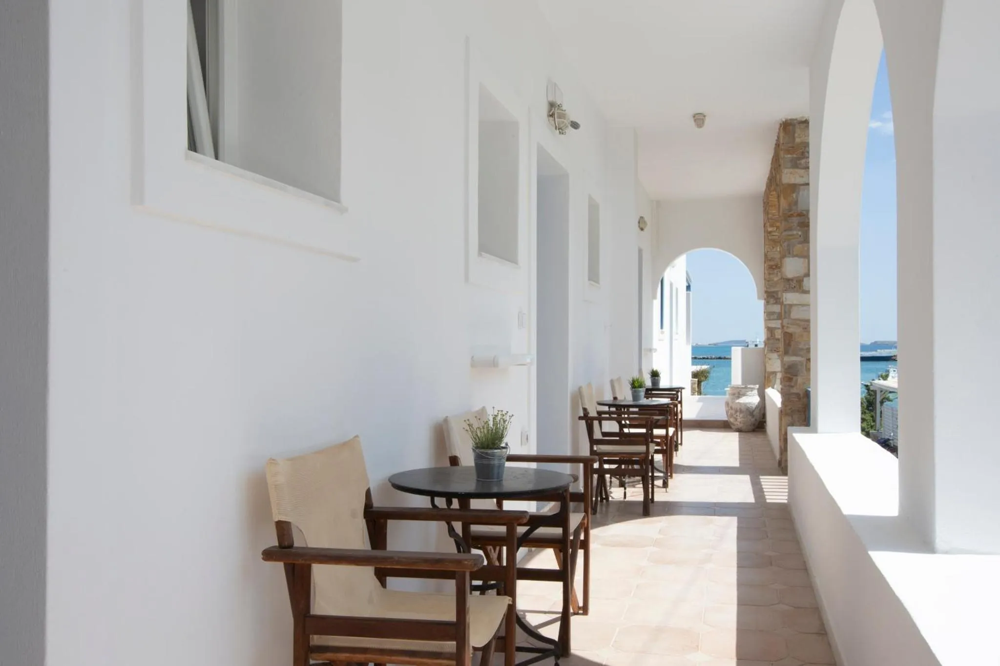 Terrasse ombragée avec tables et chaises donnant sur la mer.