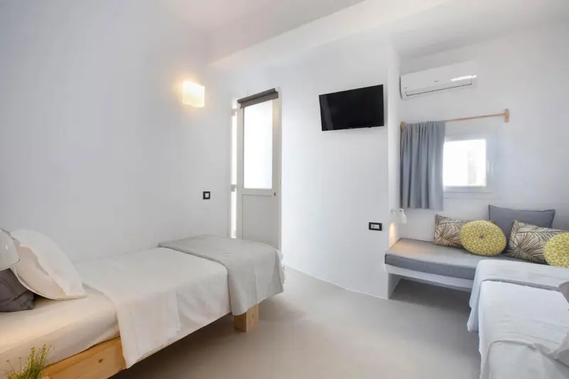 Une chambre lumineuse avec deux lits simples et un canapé.
