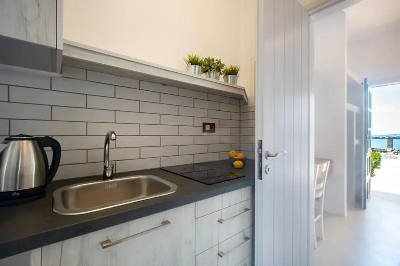 Une kitchenette moderne avec un évier, des plaques de cuisson et une bouilloire.