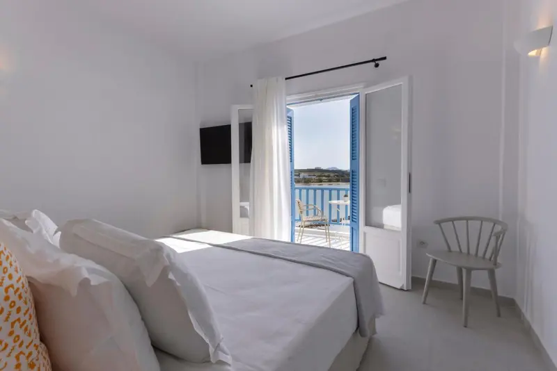 Une chambre lumineuse avec un lit et un accès à un balcon.