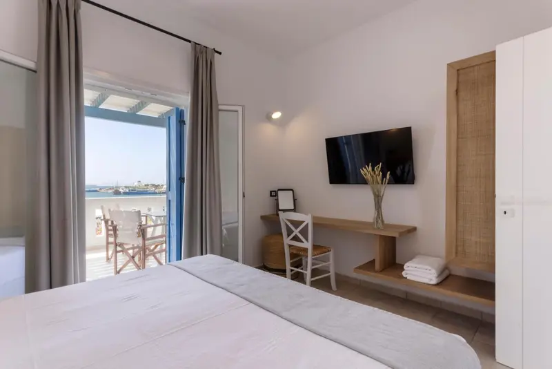 Une chambre lumineuse avec un lit et un bureau donnant sur une terrasse.