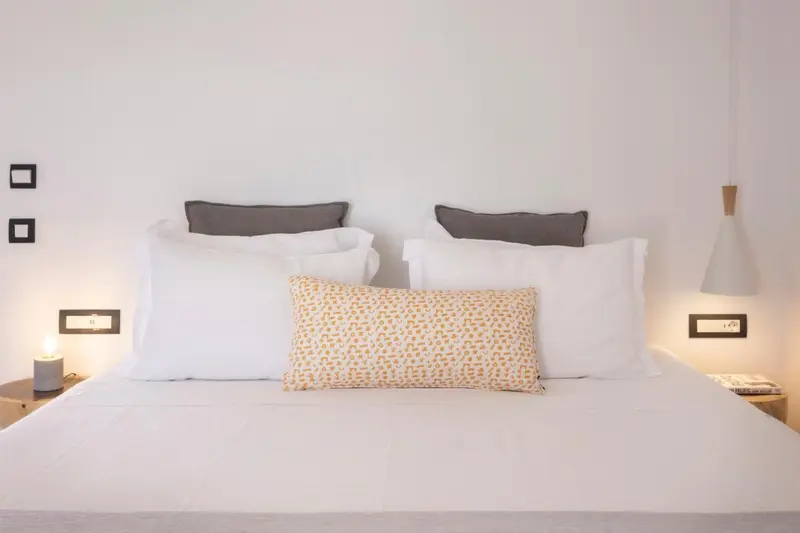 Un lit double avec des oreillers blancs et un coussin décoratif.