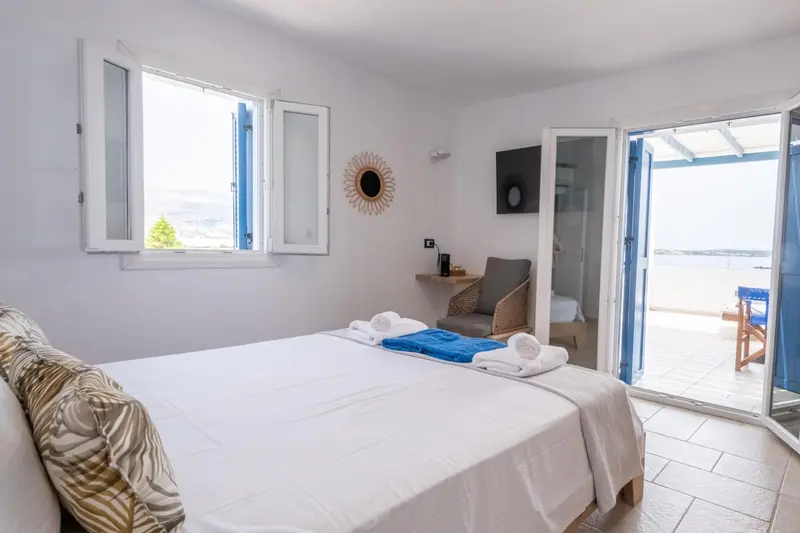 Une chambre lumineuse avec un lit fait et un accès à une terrasse.
