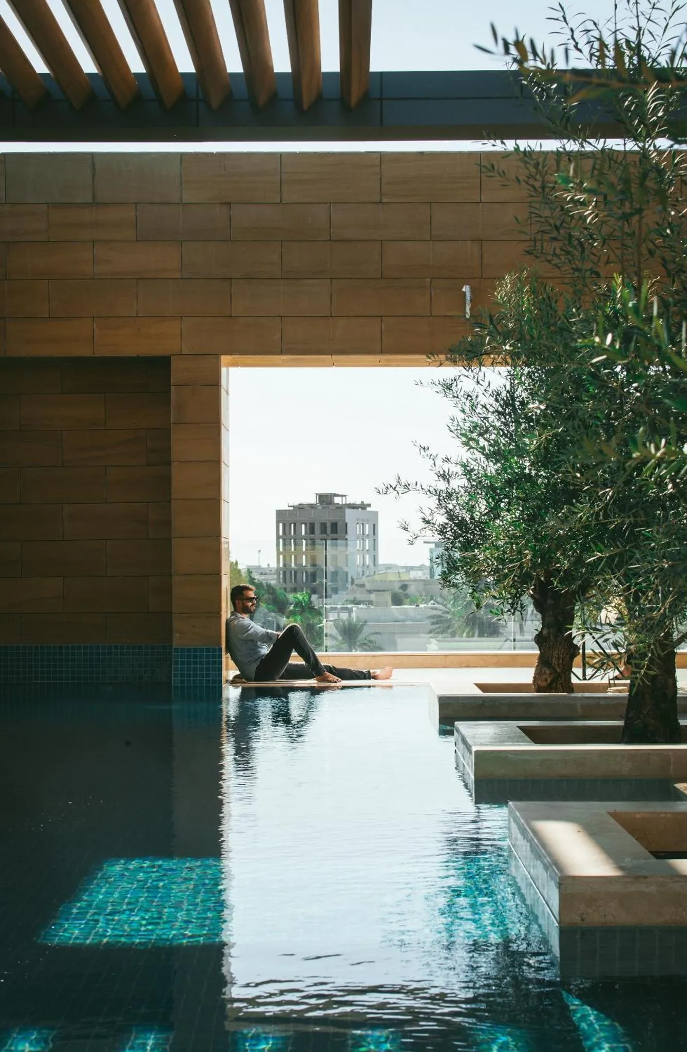 Une personne est assise au bord d'une piscine rectangulaire.