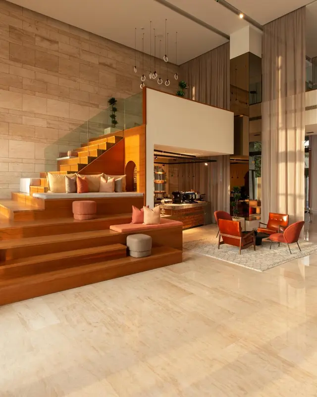 Un espace intérieur lumineux avec un escalier en bois et des assises confortables.