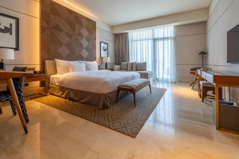 Une chambre lumineuse avec un grand lit et un espace salon.