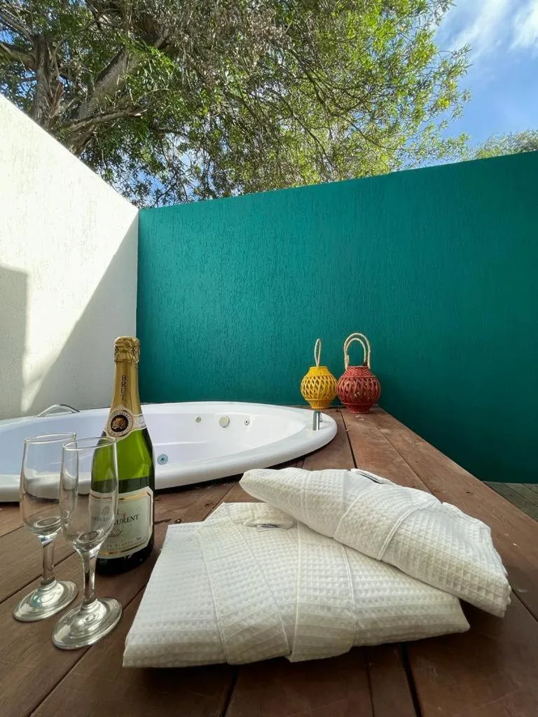 Un jacuzzi extérieur avec des bouteilles et des verres sur une terrasse en bois.