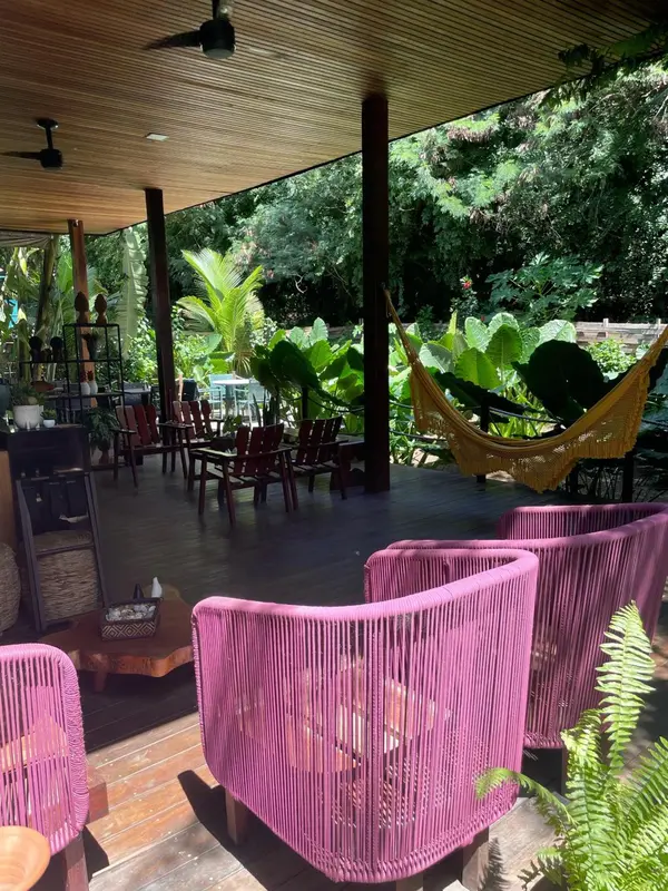 Espace de détente extérieur avec mobilier coloré et végétation luxuriante.