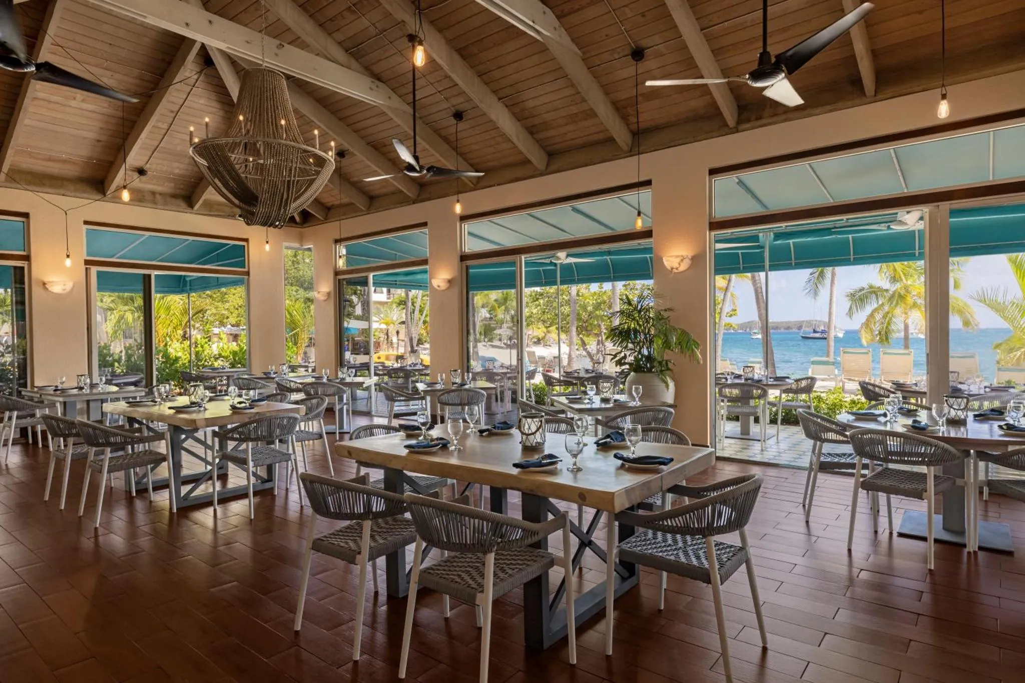 Une salle lumineuse avec des tables dressées face à une vue sur la mer.