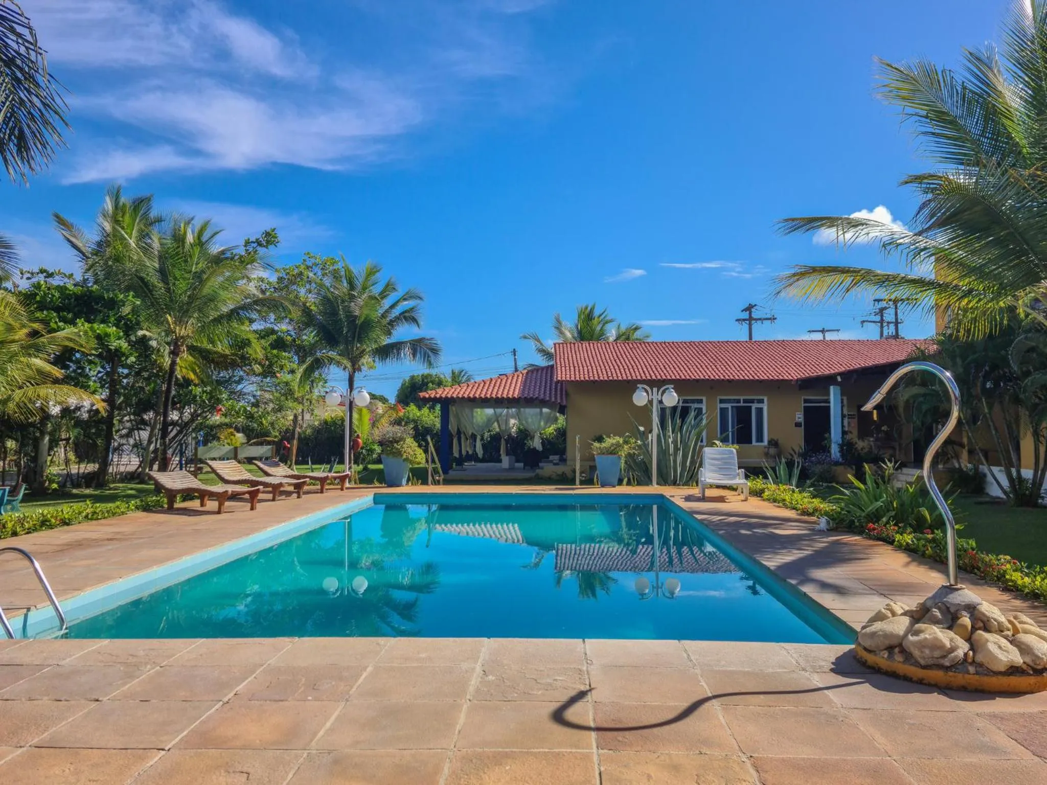 Une piscine rectangulaire bordée d'une terrasse ensoleillée avec des transats.