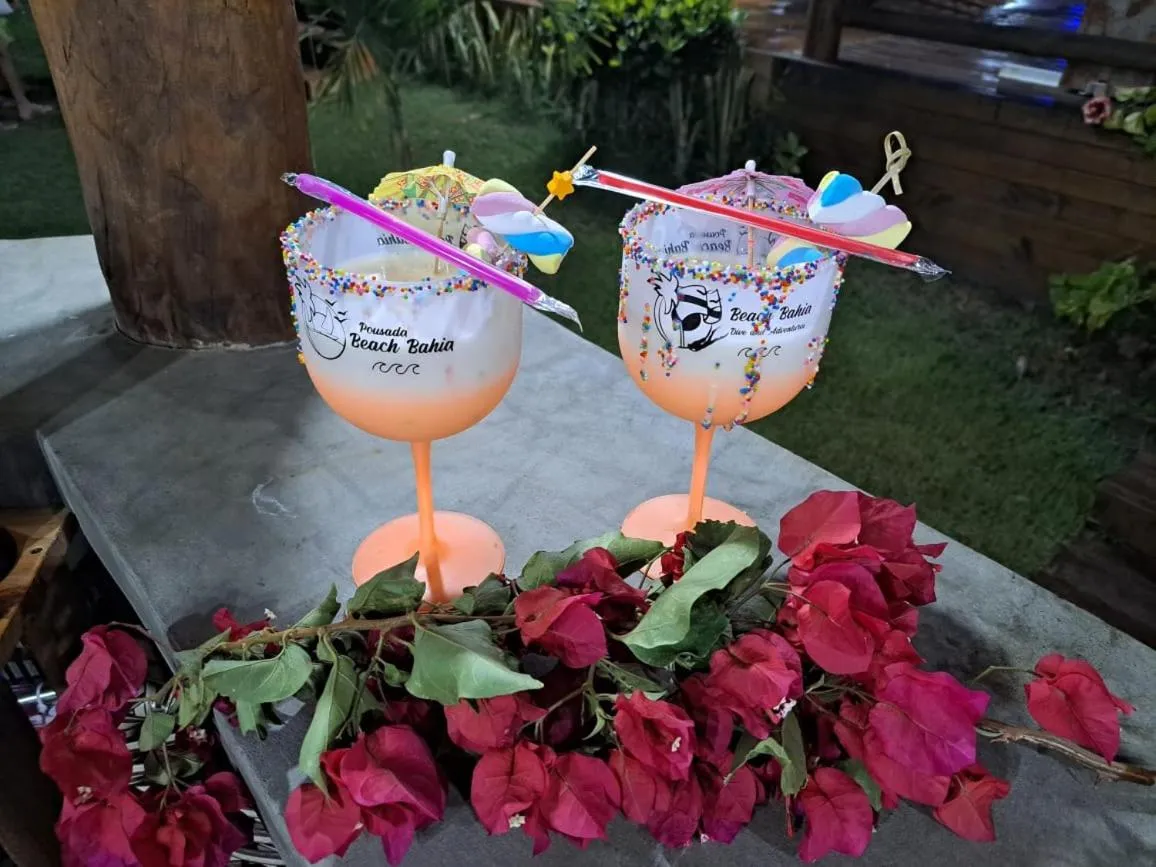 Deux cocktails colorés sont présentés sur une table en béton, décorés de fleurs roses.