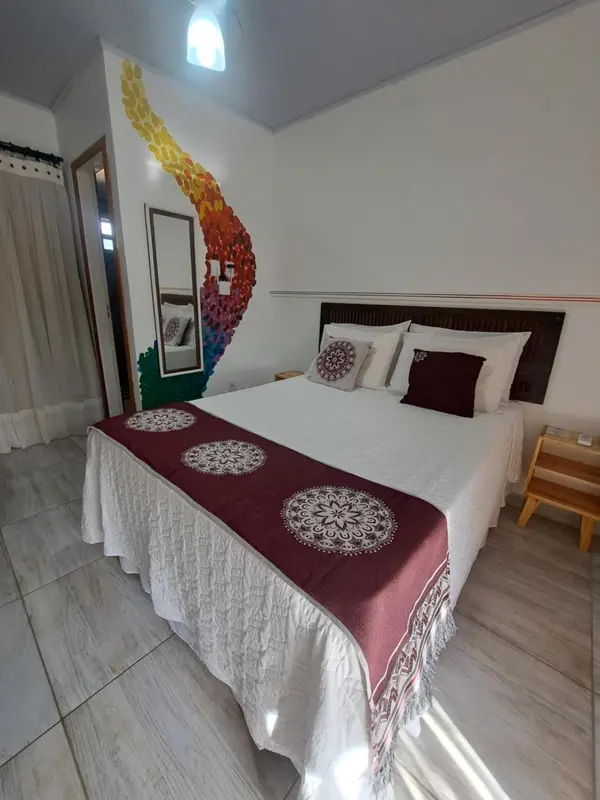 Une chambre lumineuse avec un grand lit recouvert d'une courtepointe blanche et de coussins.