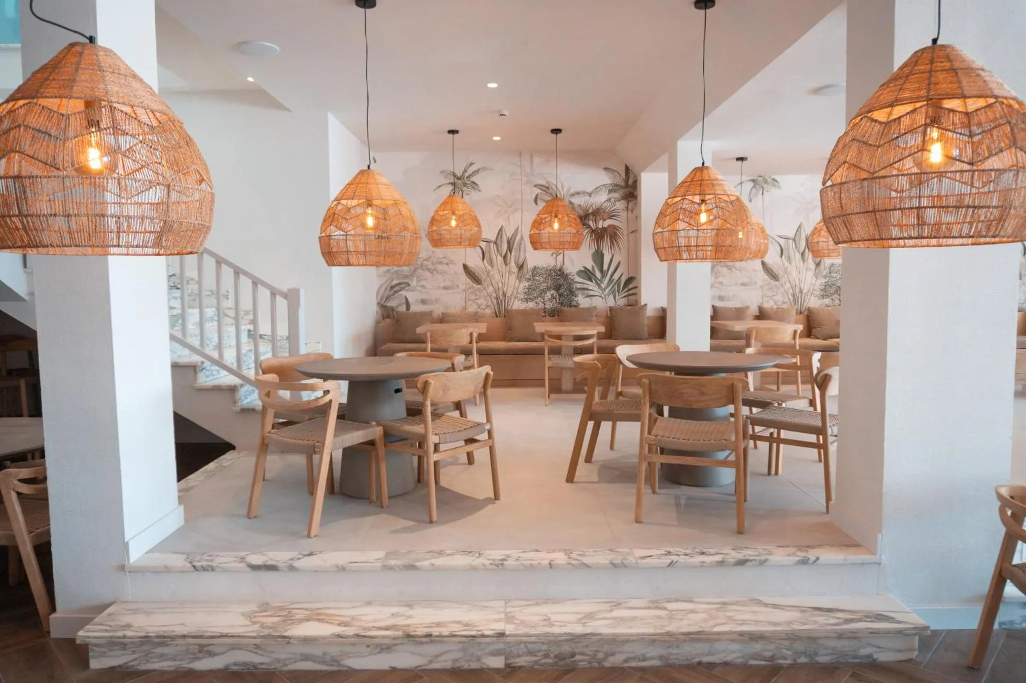 Une salle lumineuse avec des tables et des chaises en bois, décorée de suspensions en rotin.