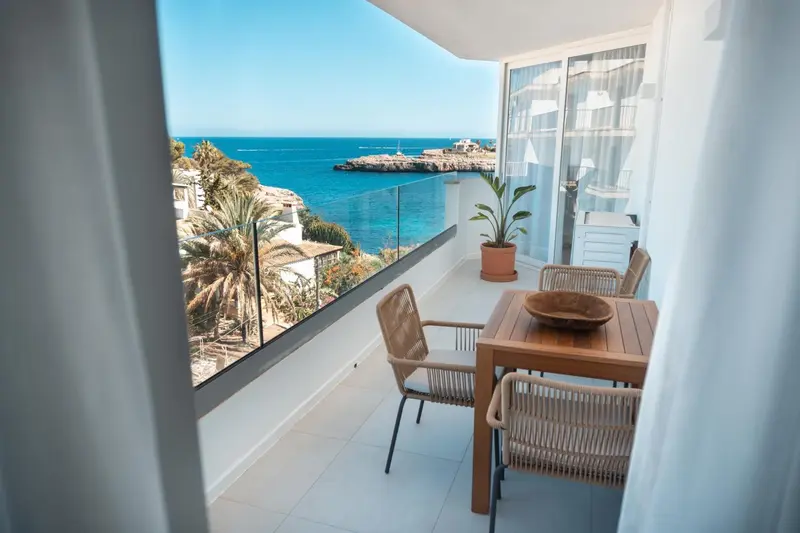 Une terrasse avec une table et des chaises offre une vue sur la mer et la côte.