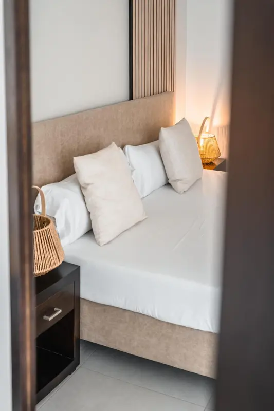 Un lit blanc avec plusieurs oreillers dans une chambre lumineuse.
