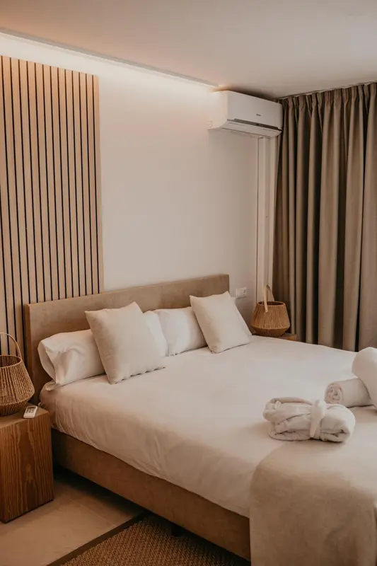 Une chambre lumineuse avec un grand lit recouvert de coussins blancs.