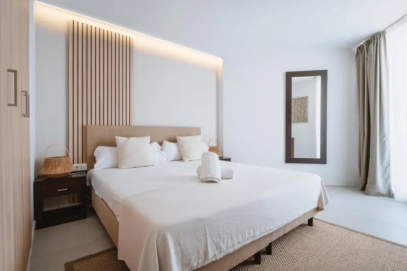 Une chambre lumineuse avec un grand lit recouvert de blanc.