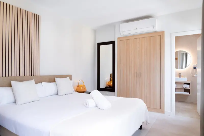 Une chambre lumineuse avec un grand lit recouvert de linge blanc et un mur texturé en bois.