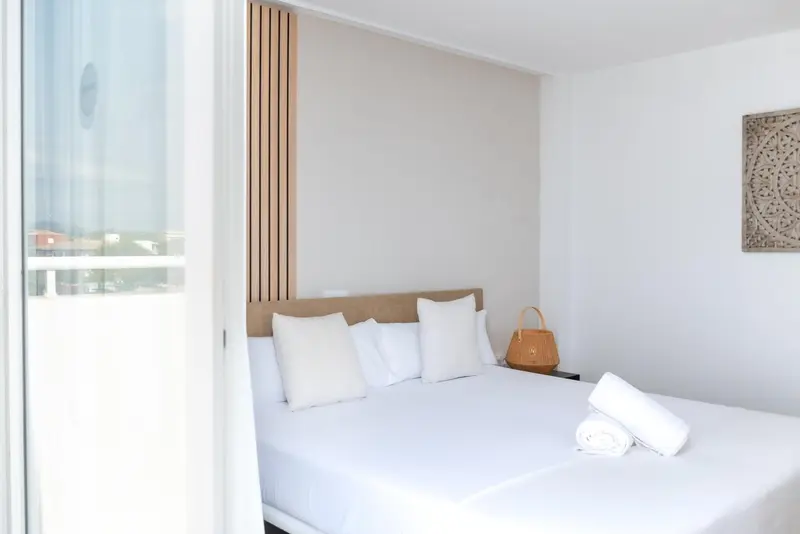 Une chambre lumineuse avec un grand lit recouvert de draps blancs.