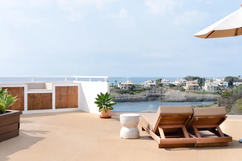 Deux transats sur une terrasse avec vue sur la mer et la côte.