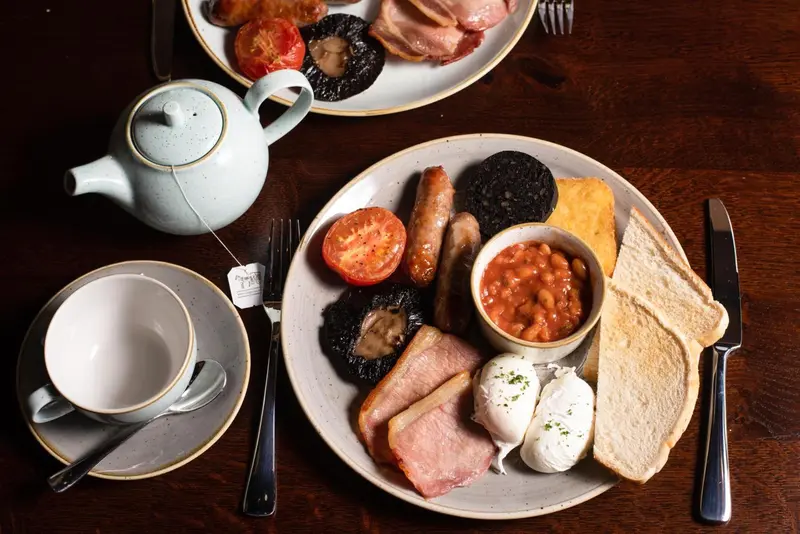 Assiettes garnies d'un petit-déjeuner anglais copieux avec œufs pochés, haricots, saucisses et bacon.