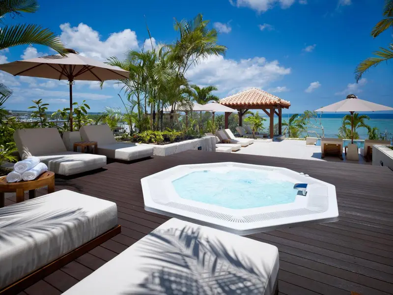 Terrasse avec transats, jacuzzi et végétation tropicale.