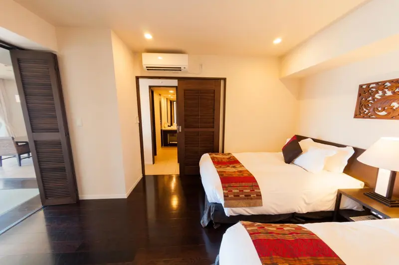 Une chambre lumineuse avec deux lits simples et un accès à un espace extérieur.