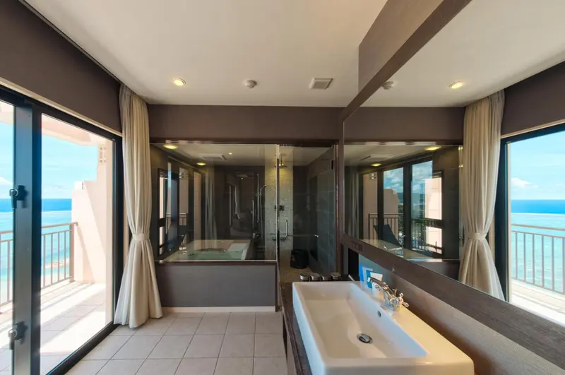 Une salle de bain lumineuse avec baignoire et douche à l'italienne offre une vue sur la mer.