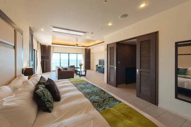 Une chambre spacieuse avec un grand lit et un espace salon lumineux.