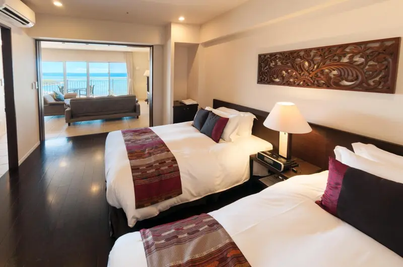Une chambre lumineuse avec un grand lit et un espace salon ouvert sur une vue mer.