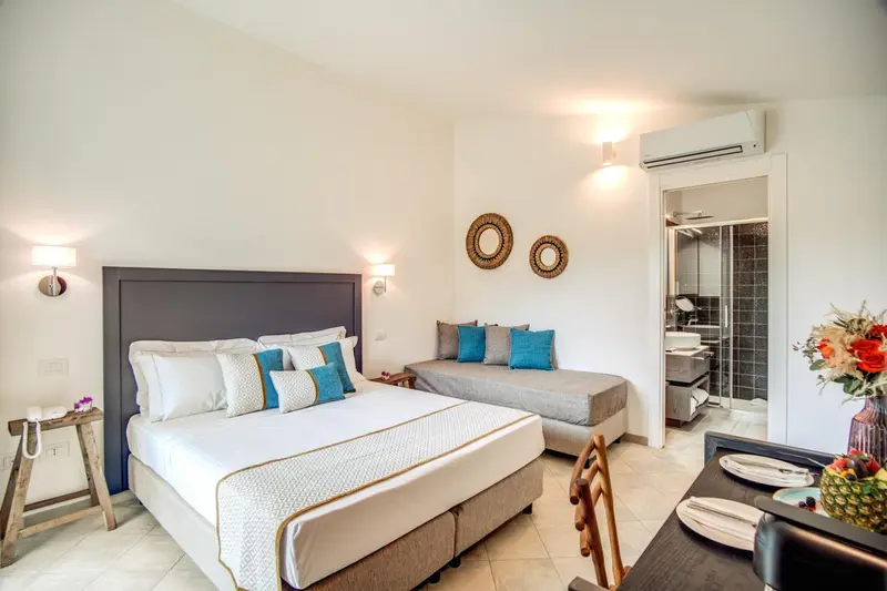 Chambre lumineuse avec un grand lit et un coin repas.