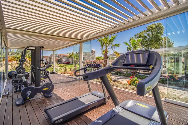 Une salle de sport en plein air avec des équipements de fitness et une vue sur un jardin.