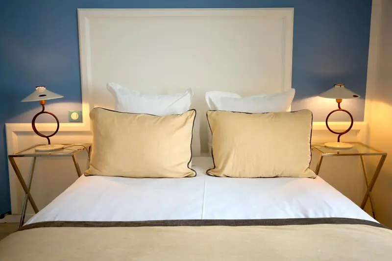 Un lit double avec des oreillers et des lampes de chevet.
