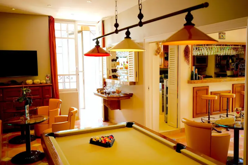 Une pièce de séjour lumineuse avec un billard et un bar.