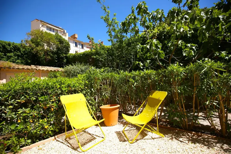 Deux chaises longues jaunes invitent à la détente dans un jardin verdoyant.