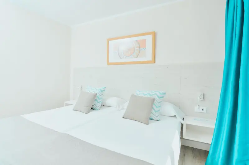 Lit double avec oreillers dans une chambre lumineuse.